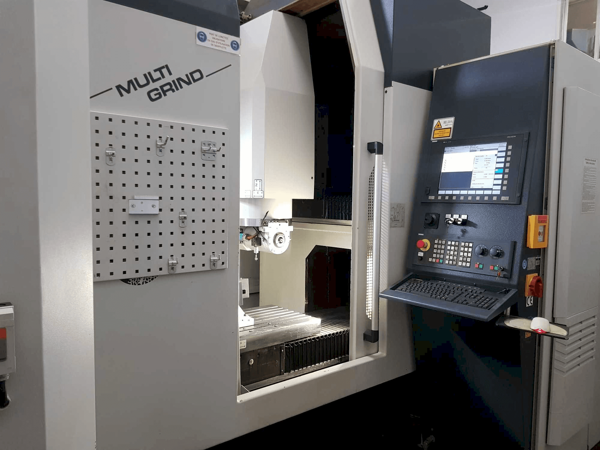 Maszyna CNC Multi Grind z widokiem z przodu, z panelem sterowania, tablicą do przechowywania i otwartym obszarem roboczym.
